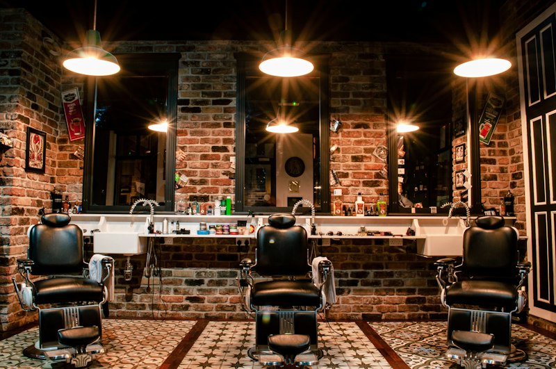 Suasana interior barbershop FORM dengan kursi kulit klasik dan cermin berlampu hangat